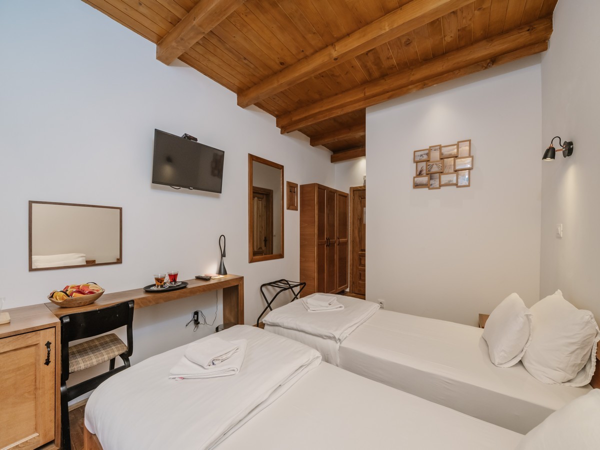 Hotelska soba sa dva kreveta, drvenim stropom od greda i modernim nameštajem