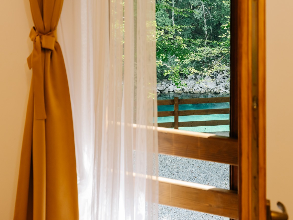 Pogled iz hotelske sobe kroz otvorena vrata na rijeku sa zelenom vegtacijom