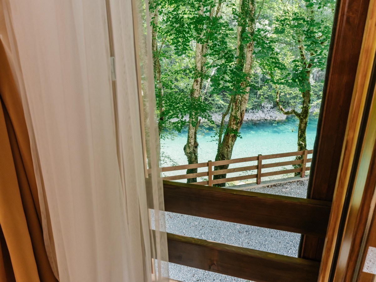 Pogled iz hotelske sobe na terasu sa vidom na bujnu šumu i tirkiznu reku