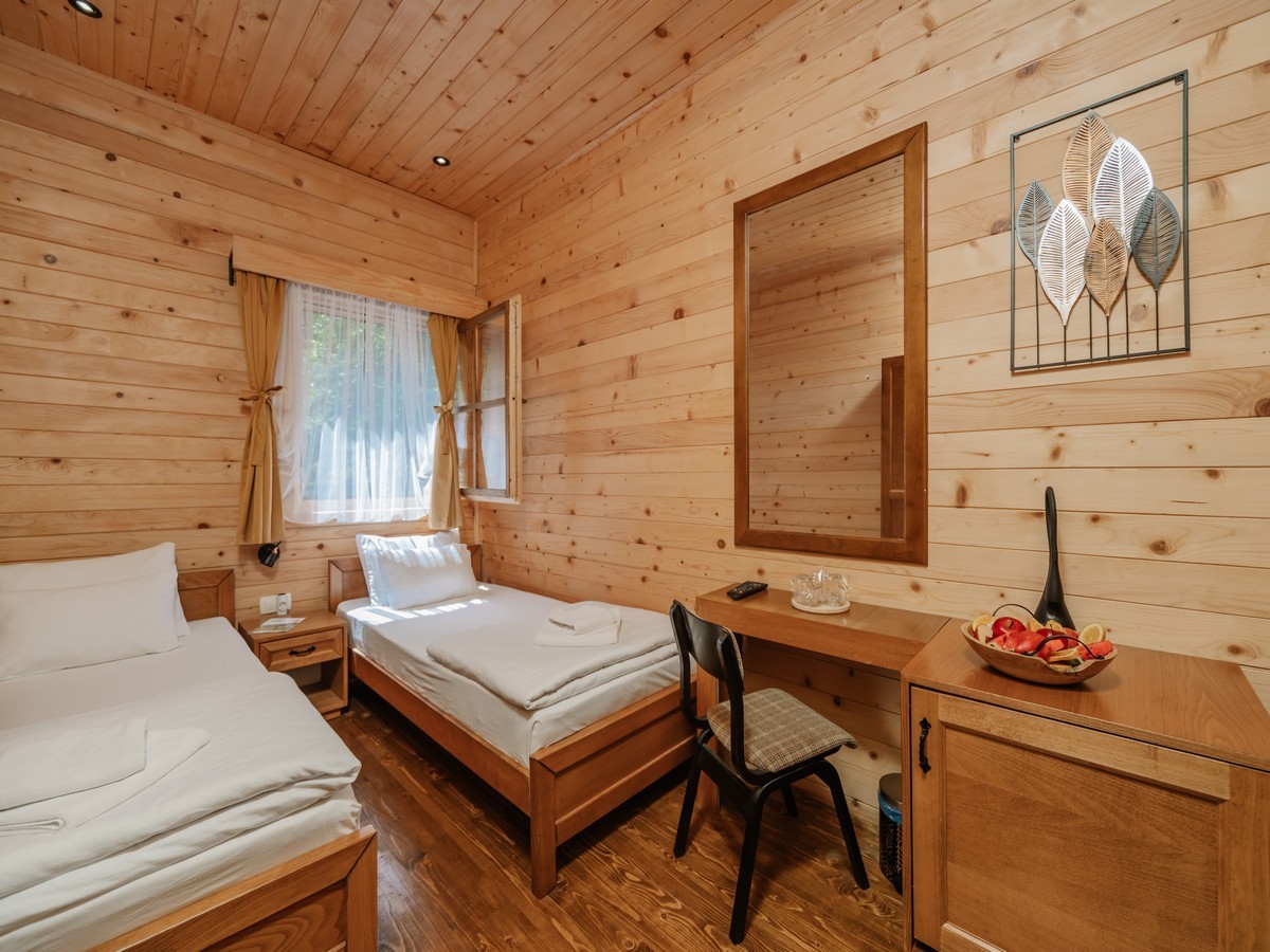 Unutrašnjost drvene bungalow sobe sa dva kreveta, pisaćim stolom i modernom dekoracijom