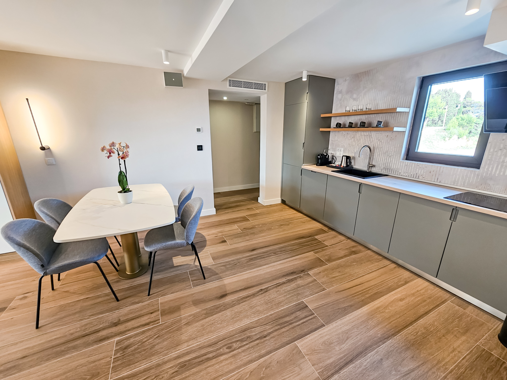 Moderna hotelska soba sa kuhinjom, belo-sivim enterijerom i parketom