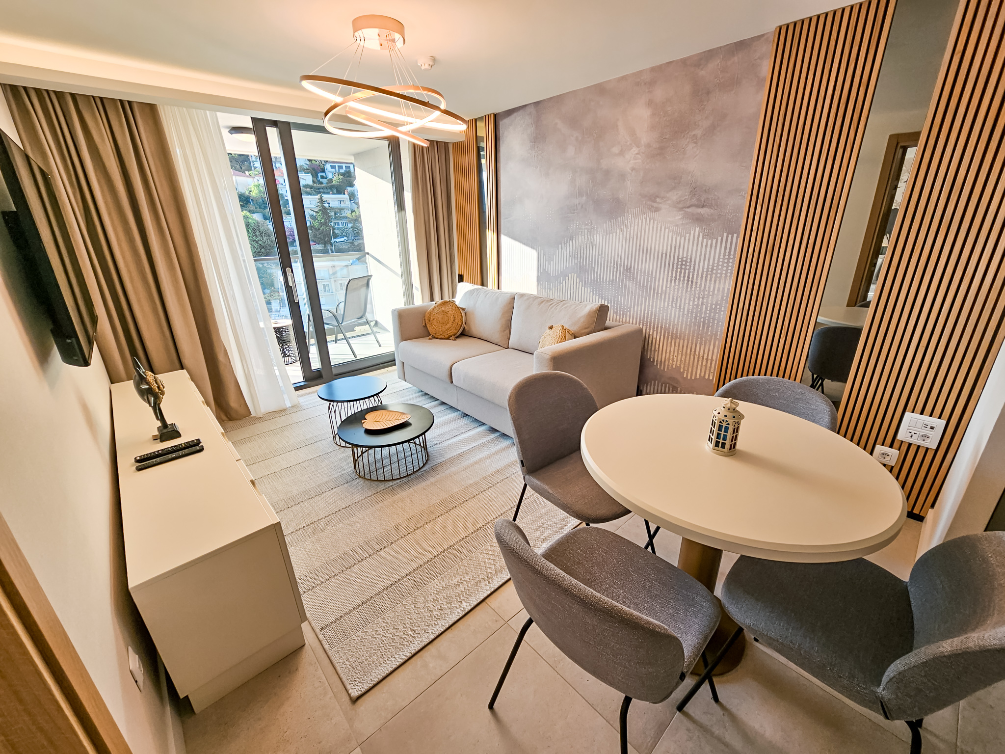 Moderan hotelski apartman sa dnevnom sobom, sofom, stolom i pogledom na balkon