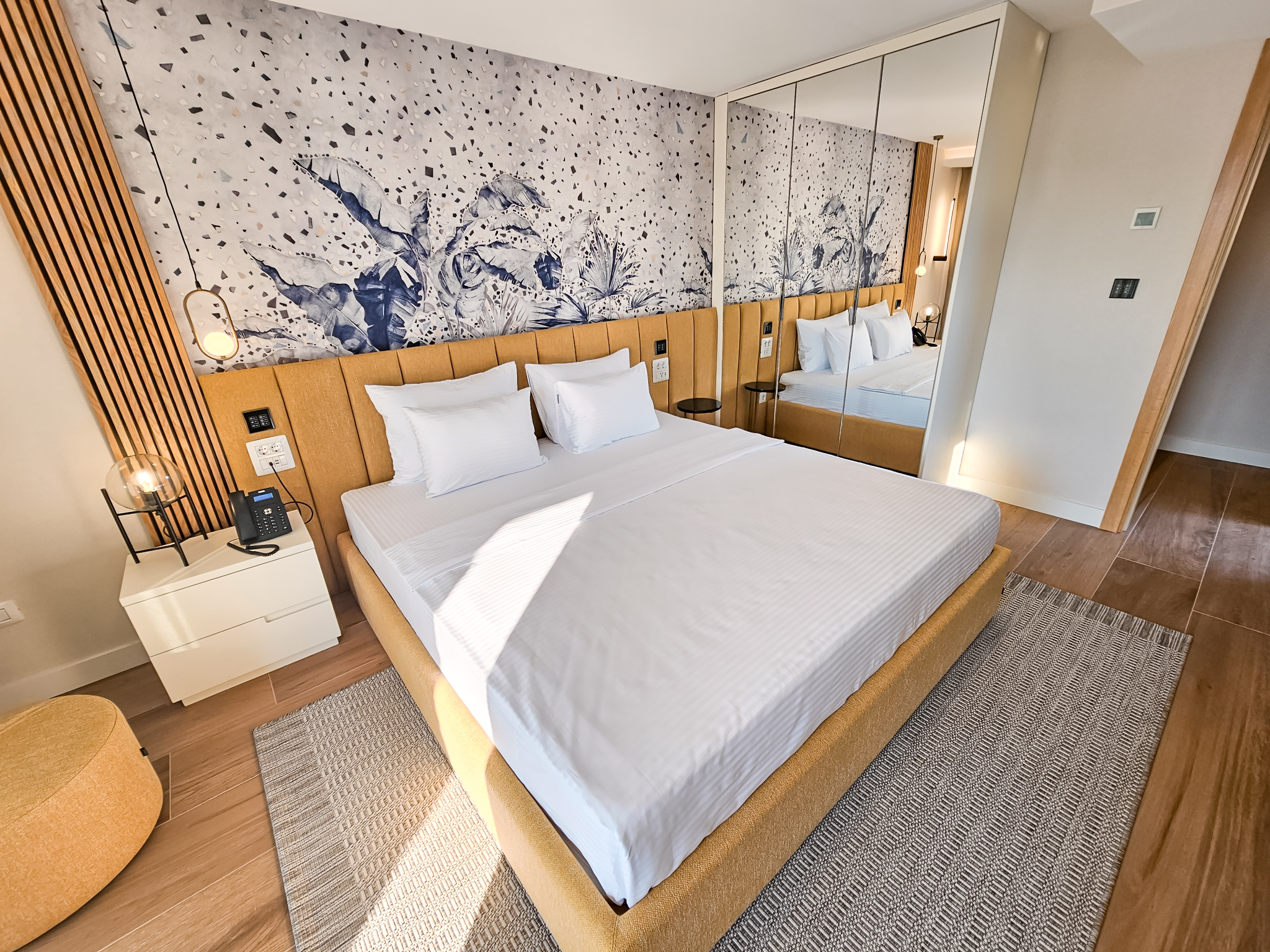 Moderna hotelska soba sa dvokrevetnom posteљom, drvenom ogradom kreveta i umetničkim zidnim motivom sa životinjama